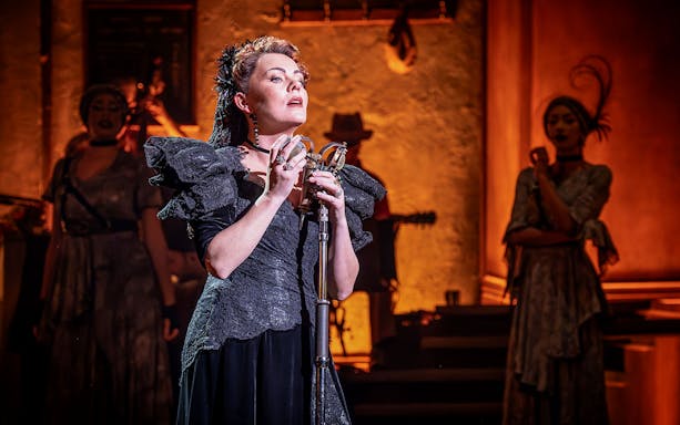 Performer singing on stage during Hadestown musical.