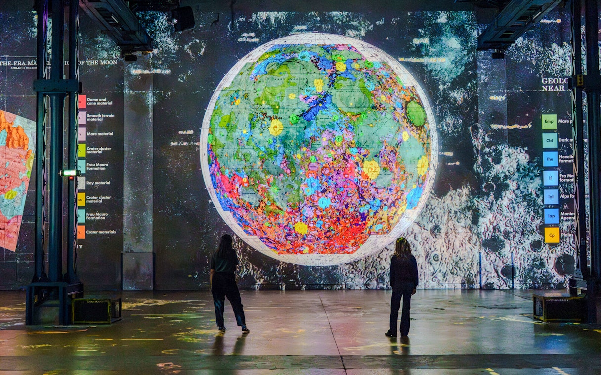 Moonwalkers Exhibition at Atelier des Lumières featuring a colorful lunar map display.