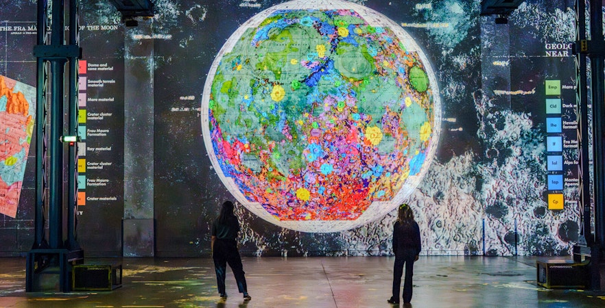 Moonwalkers Exhibition at Atelier des Lumières featuring a colorful lunar map display.