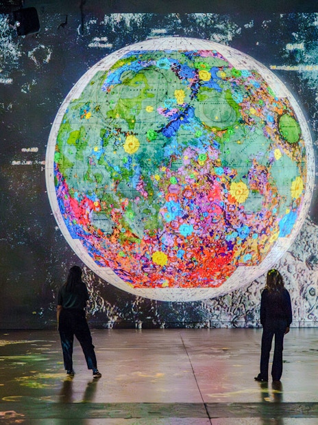 Moonwalkers Exhibition at Atelier des Lumières featuring a colorful lunar map display.