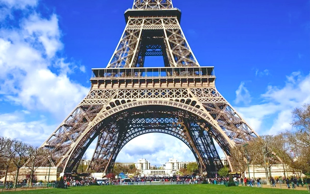 Eiffel Tower base with tourists, Paris, view from Champ de Mars.
