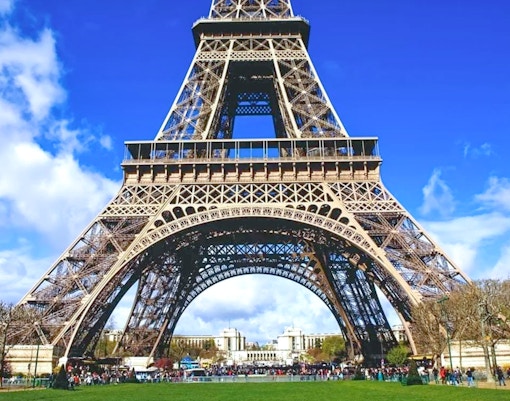 Eiffel Tower base with tourists, Paris, view from Champ de Mars.
