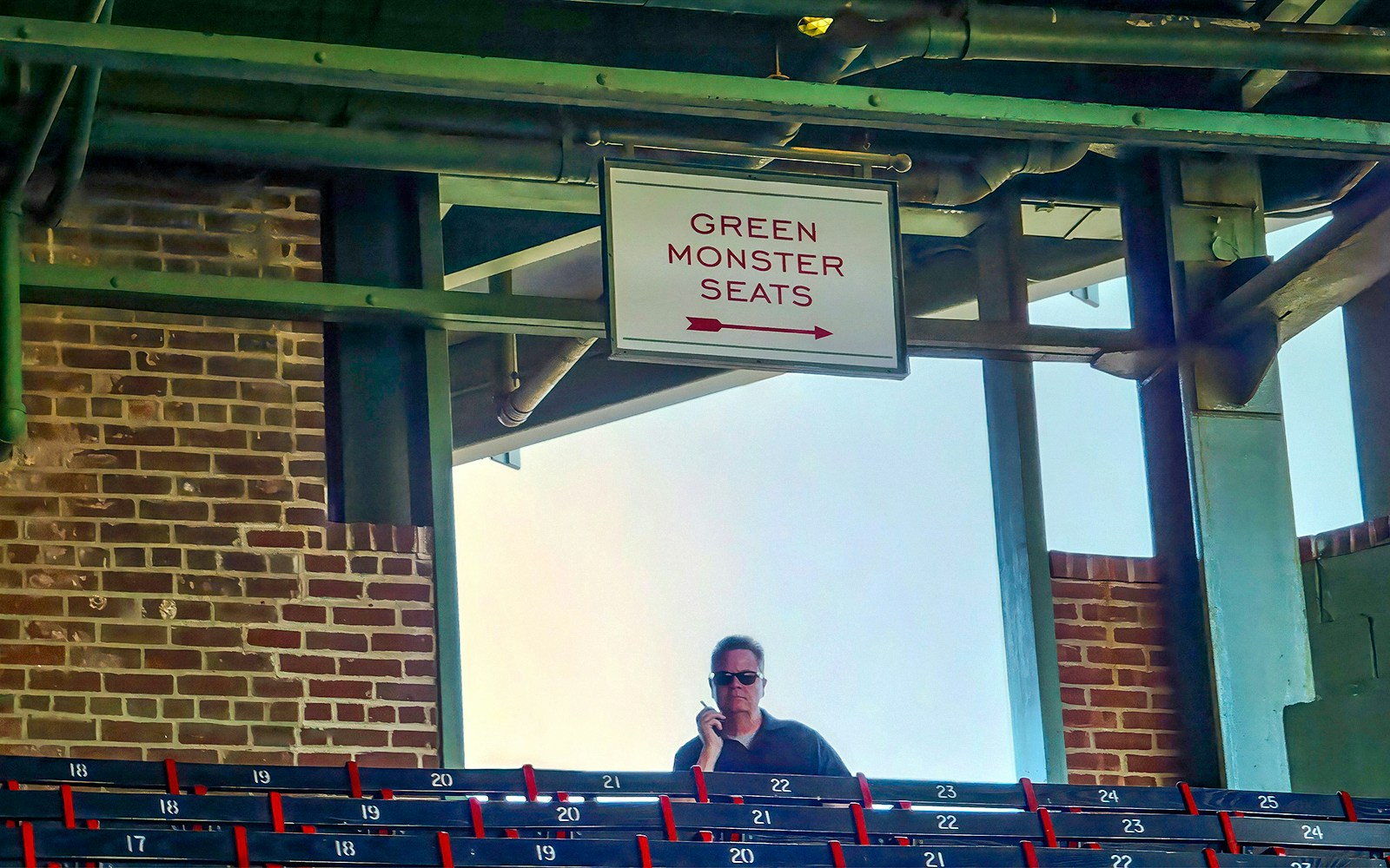 Man sitting in Fenway Park's Green Monster seats, Boston.