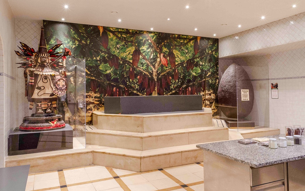 Chocolate Museum Paris exhibit featuring cacao tree mural and large chocolate sculpture.