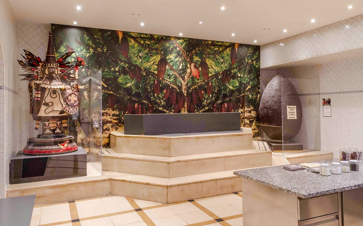 Chocolate Museum Paris exhibit featuring cacao tree mural and large chocolate sculpture.