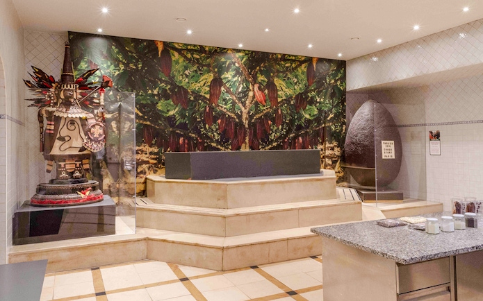 Chocolate Museum Paris exhibit featuring cacao tree mural and large chocolate sculpture.