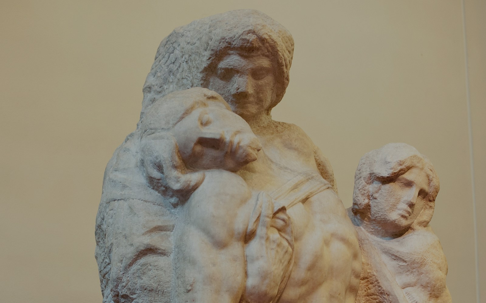 Escultura "Palestrina Pietà", de Michelangelo, exibida na Galeria Uffizi, representando uma Virgem Maria sombria embalando Jesus, acompanhada por Maria Madalena, em mármore envelhecido