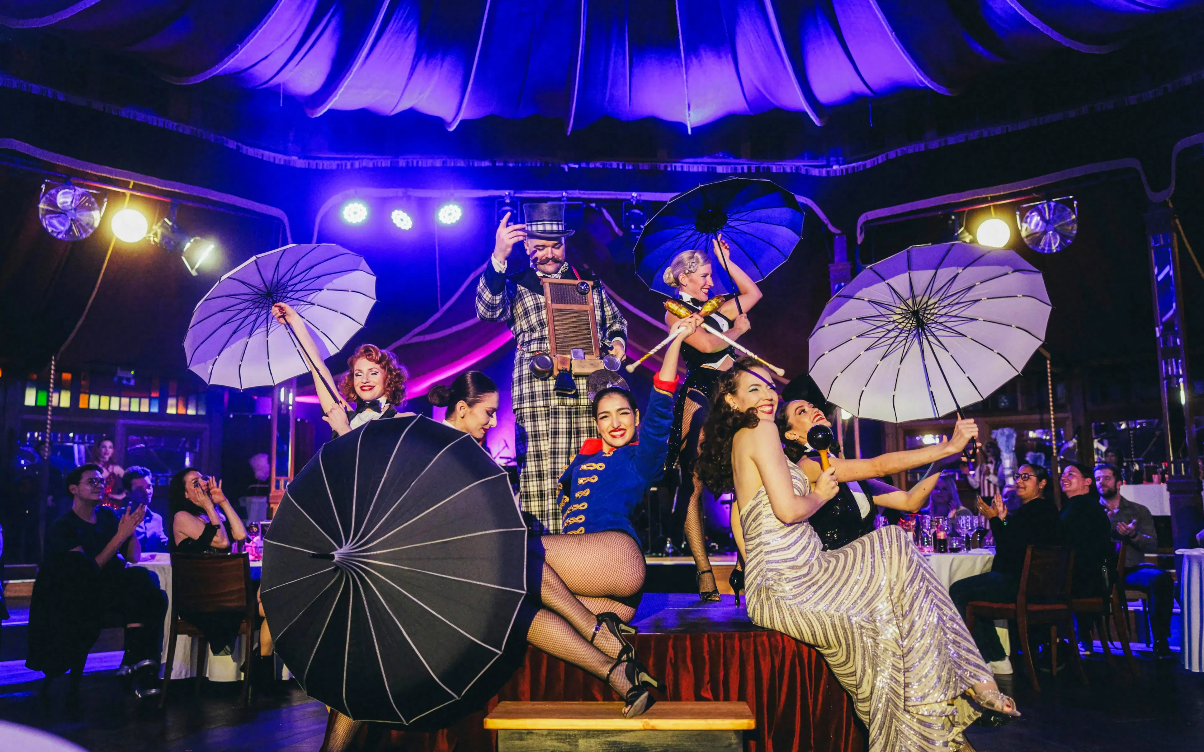 Burlesque performers with umbrellas on stage at The Mirage dinner show, Vienna.