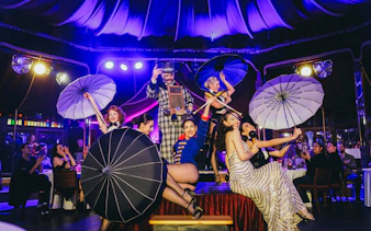 Burlesque performers with umbrellas on stage at The Mirage dinner show, Vienna.