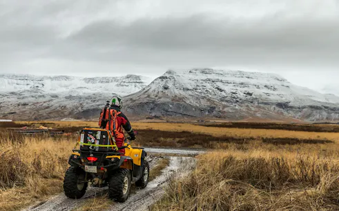 ATV rider on Iceland volcanic springs tour with snowy mountain views.
