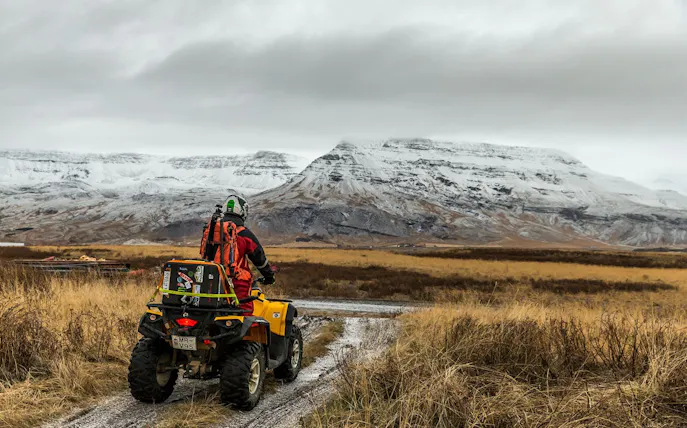 ATV rider on Iceland volcanic springs tour with snowy mountain views.