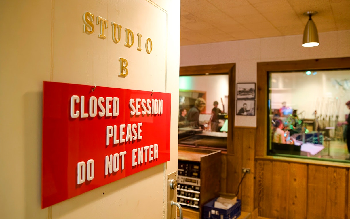 Closed session sign at Historic RCA Studio B with musicians inside recording room.
