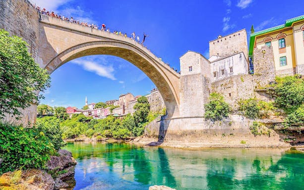 Mostar Bridge view with tourists on a private tour, Bosnia and Herzegovina.