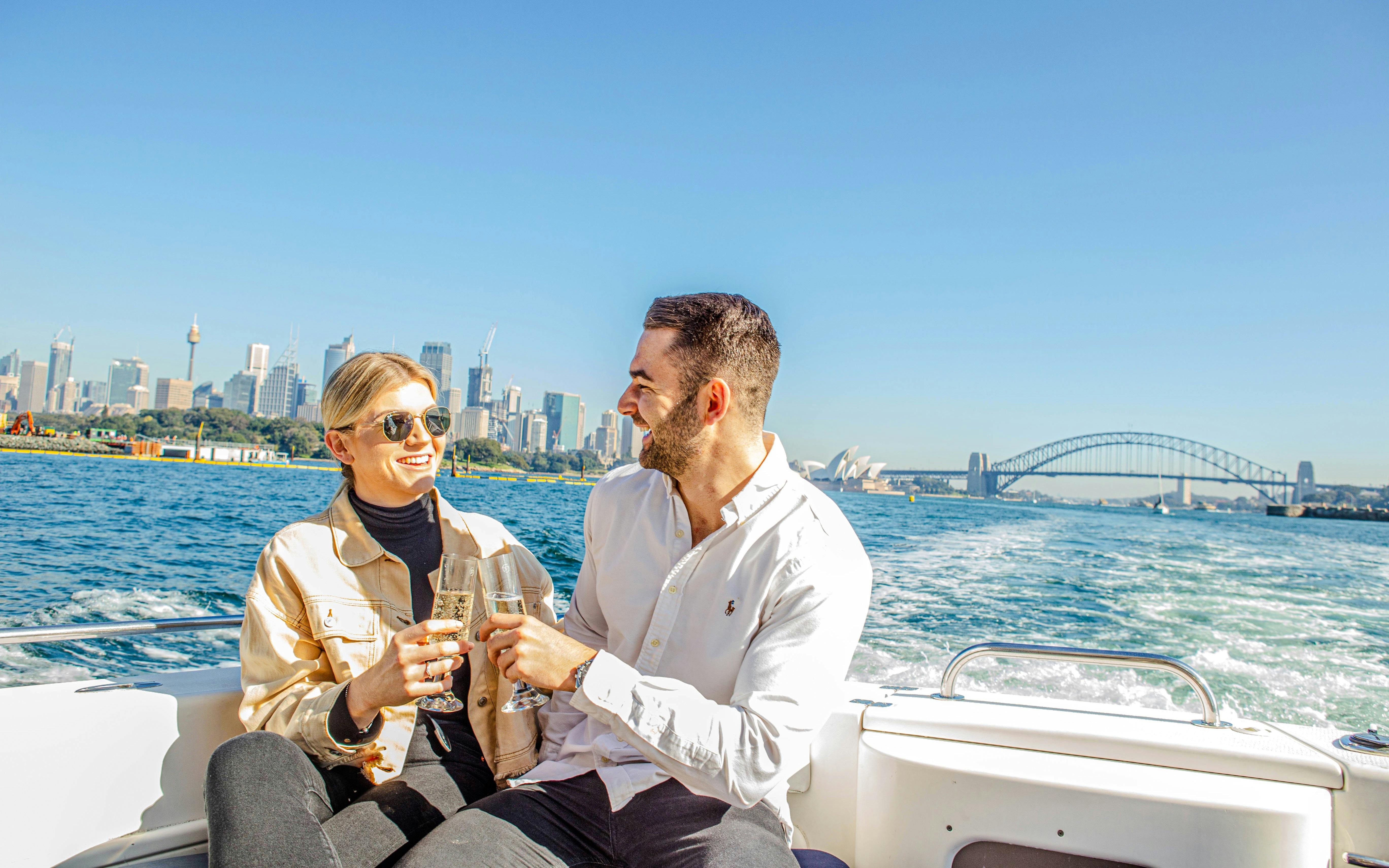 Couple enjoying champagne on a luxury cruise with Sydney Opera House and Harbour Bridge in the background.