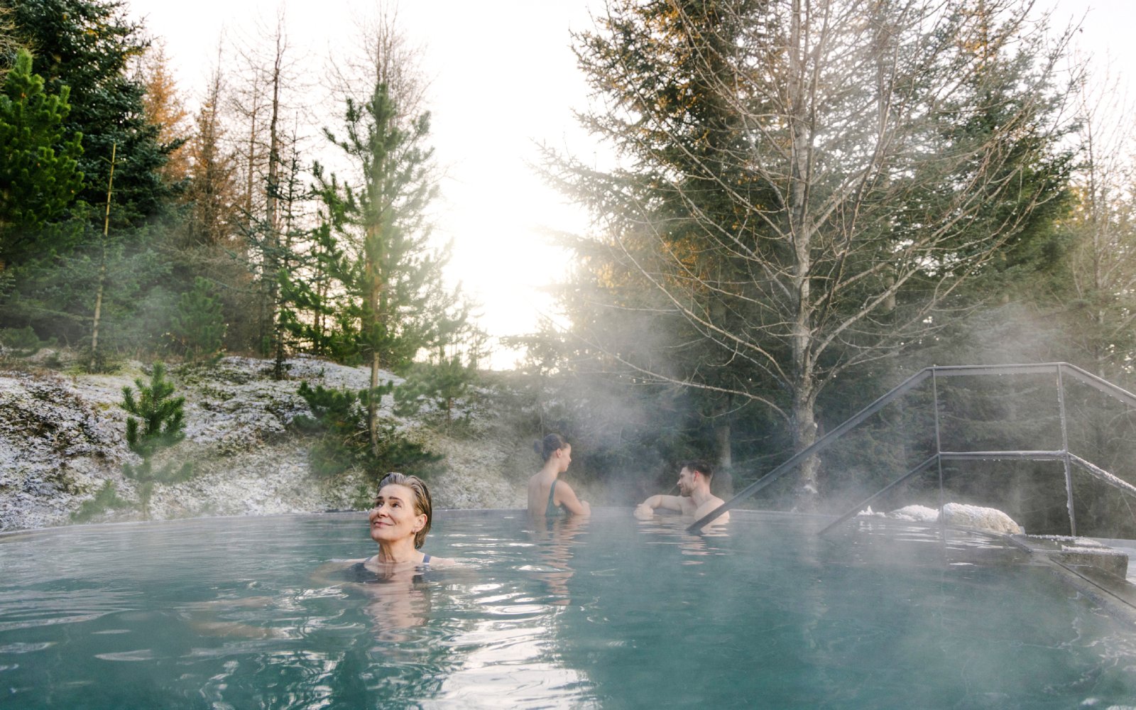Guests enjoying a warm soak in the forest pool at Laugarás Lagoon.