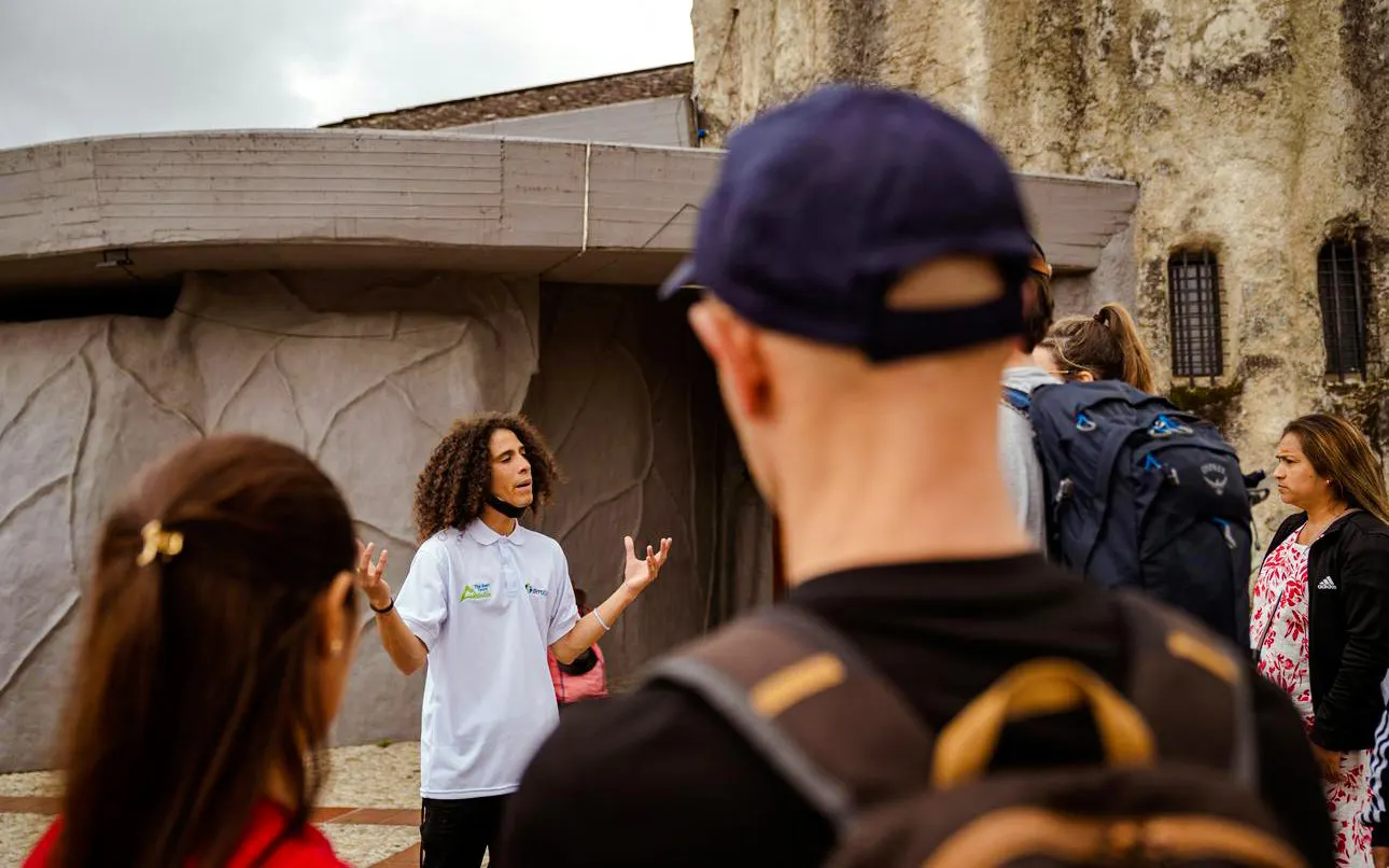 Guide leading guests on the Guatapé Gastronomic Tour near a stone building.
