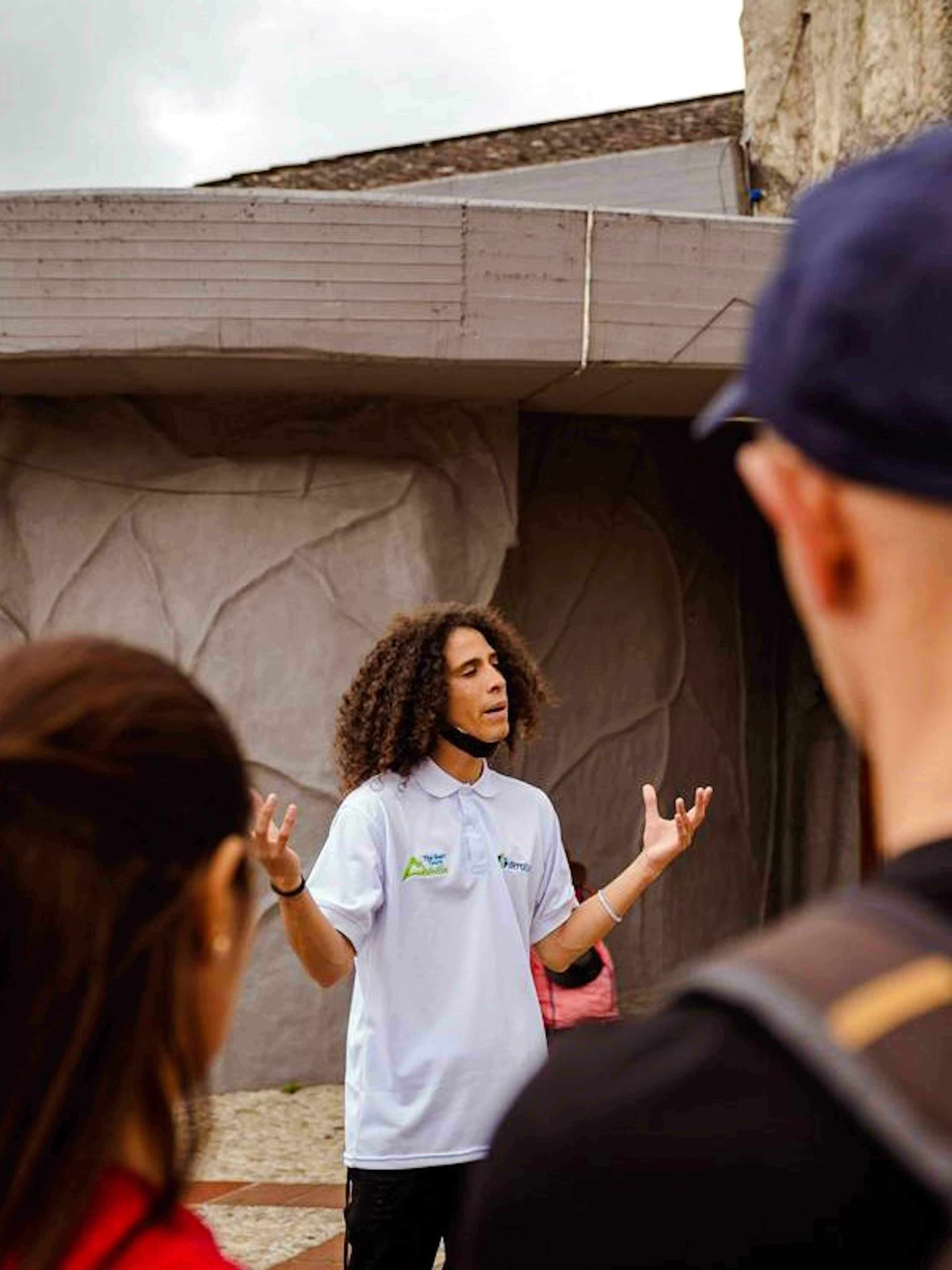 Guide leading guests on the Guatapé Gastronomic Tour near a stone building.