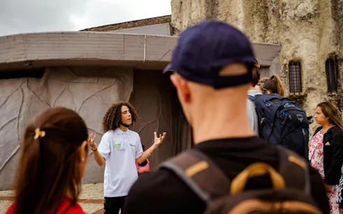 Guide leading guests on the Guatapé Gastronomic Tour near a stone building.