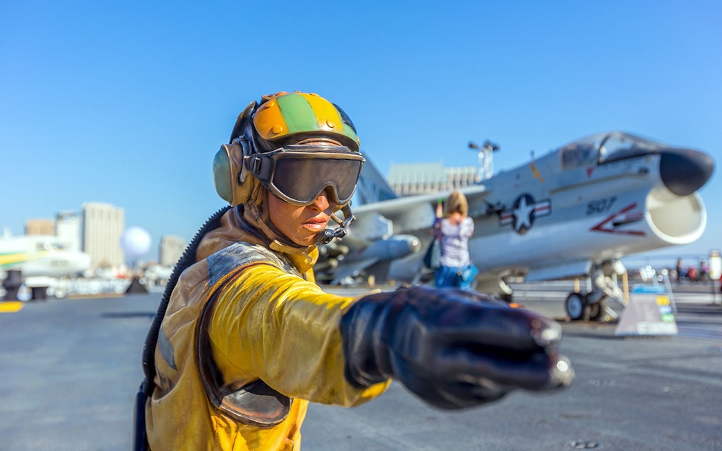 Aircraft carrier deck with crew member directing at USS Midway Museum, San Diego.