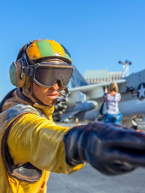 Aircraft carrier deck with crew member directing at USS Midway Museum, San Diego.