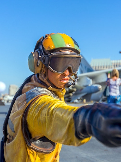 Aircraft carrier deck with crew member directing at USS Midway Museum, San Diego.