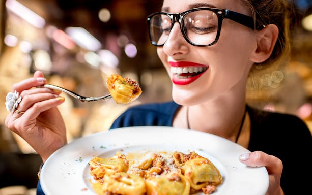 Woman enjoying tortellini on Roman cuisine tour.