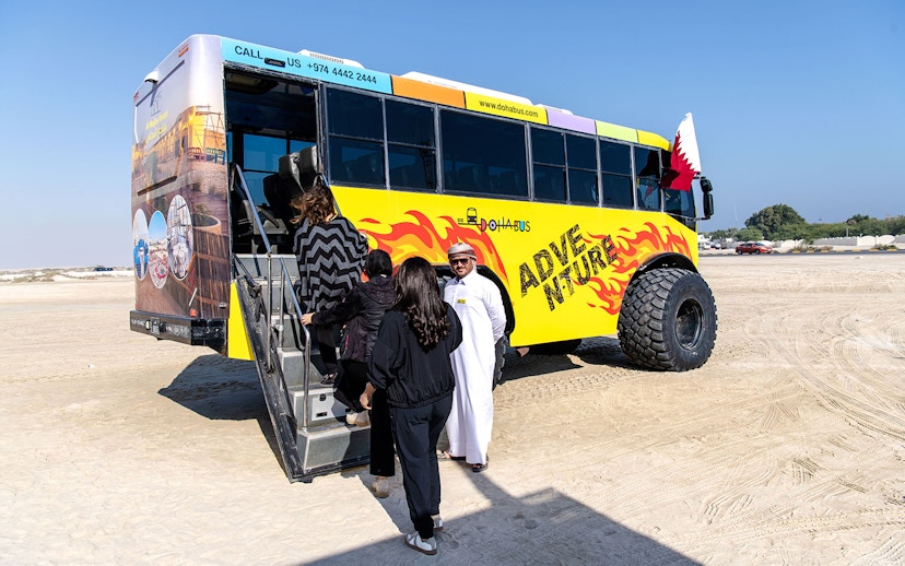 Tourists boarding Monster Bus for Doha adventure tour.