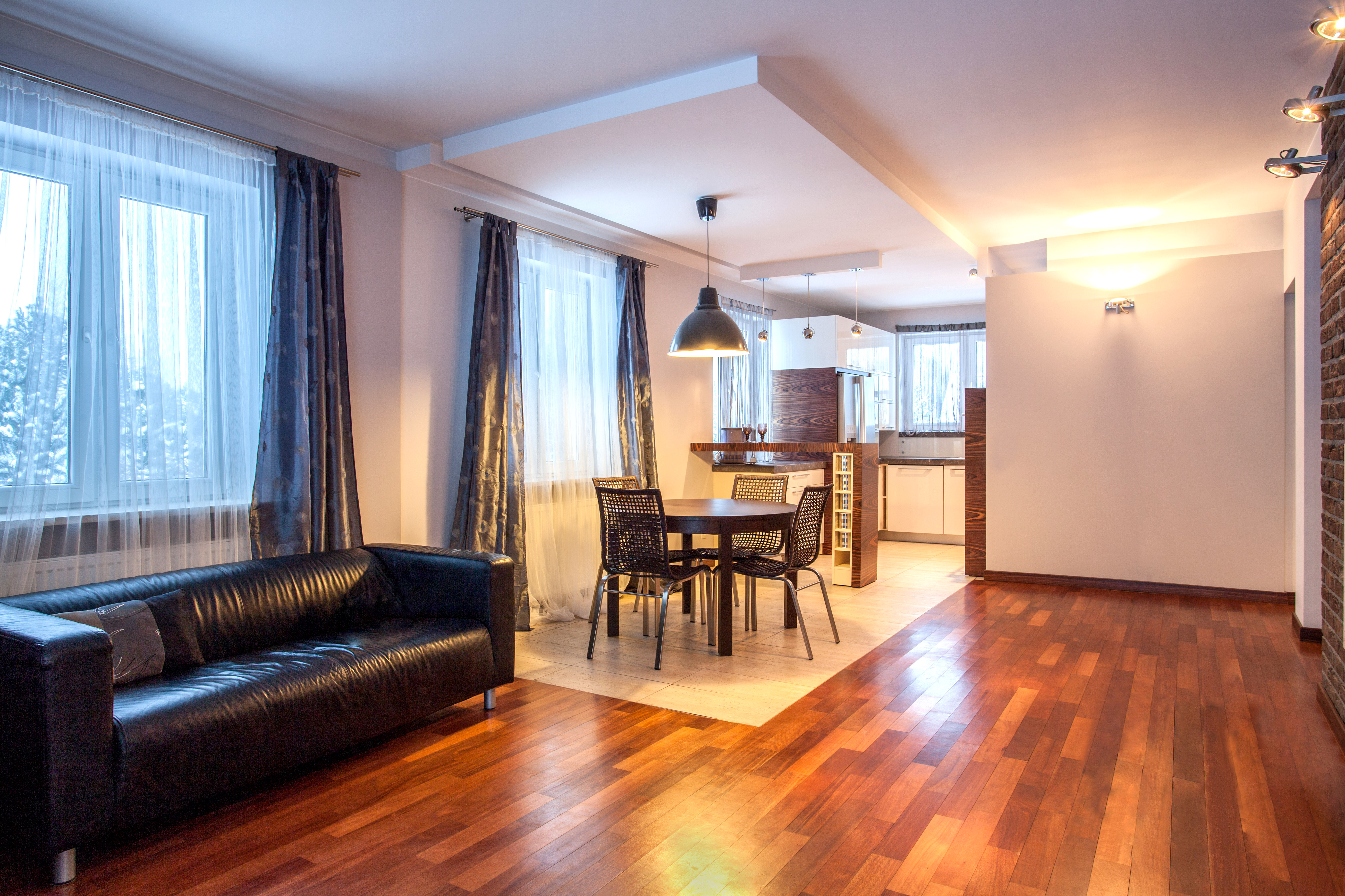 Modern living area in The Glasshouse hotel, Edinburgh, featuring a dining table and leather sofa.