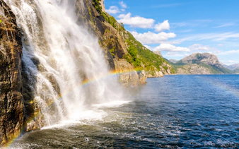Waterfall cascading into Lysefjord with a rainbow, Lysefjord, Norway.