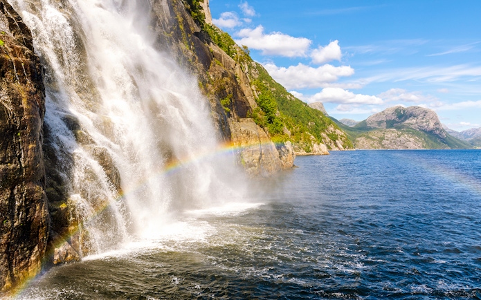 Waterfall cascading into Lysefjord with a rainbow, Lysefjord, Norway.