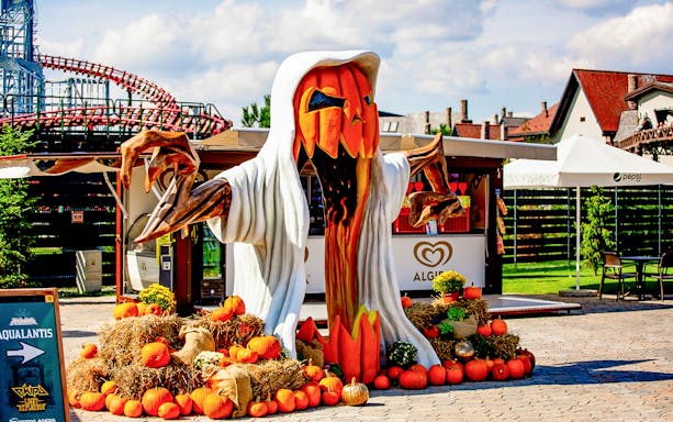 Halloween-themed pumpkin figure at Energylandia entrance with hay bales and pumpkins.