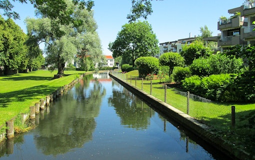 Canal view with greenery and modern buildings in Berlin.
