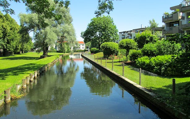 Canal view with greenery and modern buildings in Berlin.