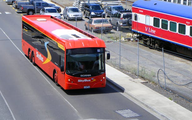 Skybus Hobart Airport Shuttle on road near train station.