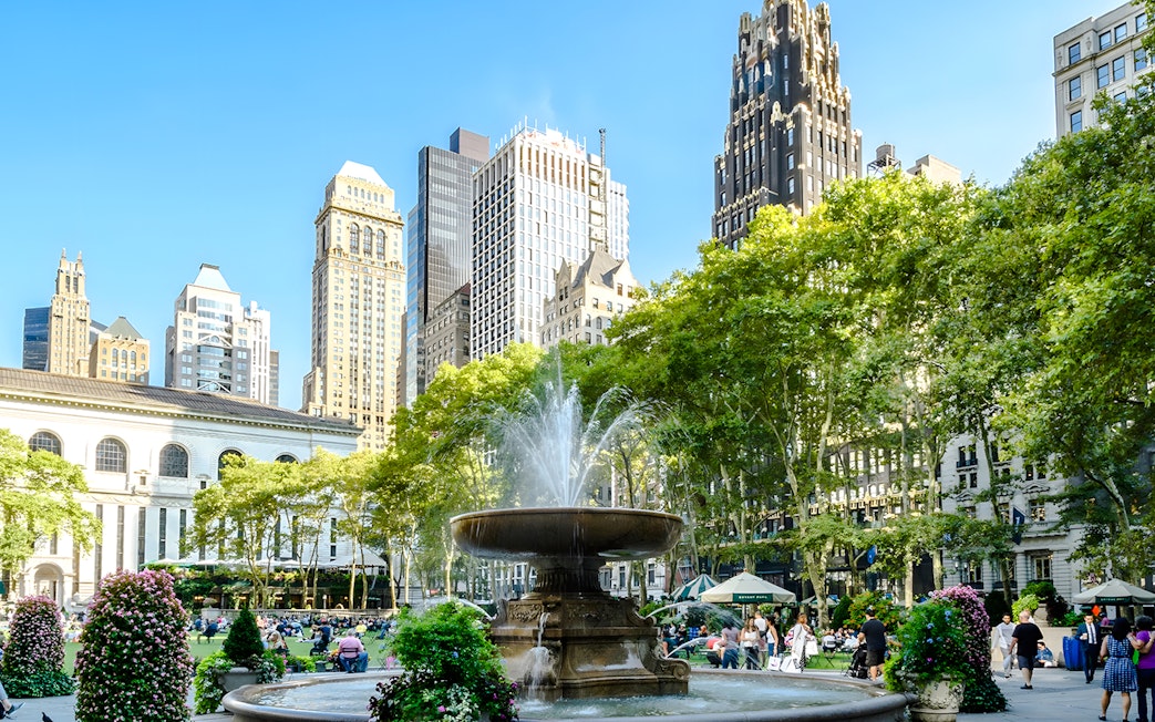 Bryant Park fountain with skyscrapers and trees in New York City.