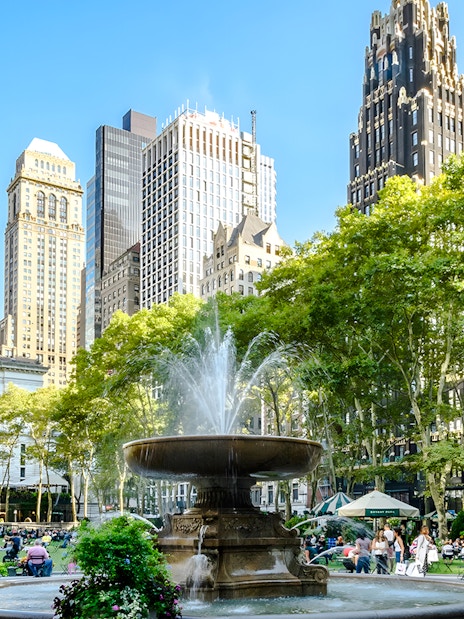 Bryant Park fountain with skyscrapers and trees in New York City.