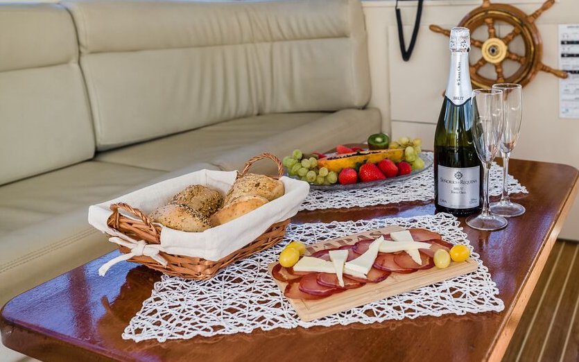 Food and drinks on a shared yacht in Tenerife, featuring bread, fruit, and champagne.