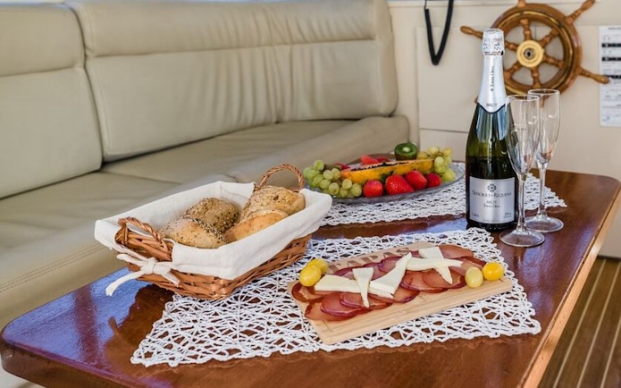 Food and drinks on a shared yacht in Tenerife, featuring bread, fruit, and champagne.
