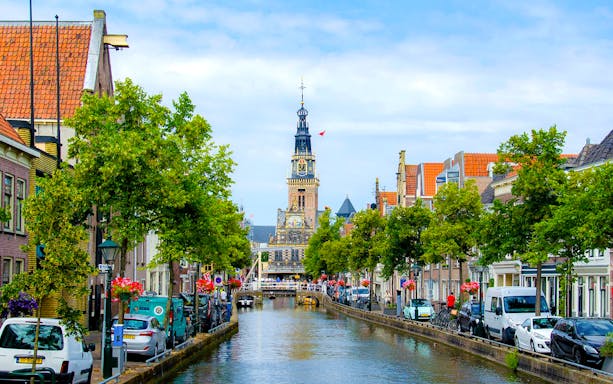 Alkmaar canal with historic buildings and church tower in the background.