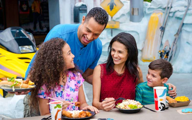 Family enjoying a meal at SeaWorld Orlando with themed decor in the background.