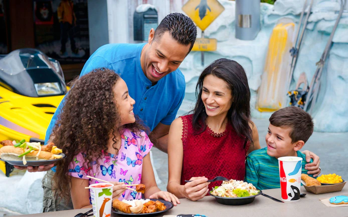 Family enjoying a meal at SeaWorld Orlando with themed decor in the background.