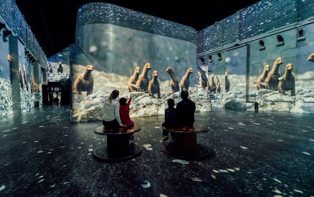 Visitors watching dinosaur projections at Dino Exhibition, Fabrique des Lumières.