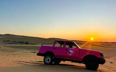 Pink jeep on Mui Ne sand dunes at sunset, part of Ho Chi Minh City ATV tour.