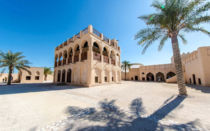 Courtyard of the National Museum of Qatar in Doha with traditional architecture and palm trees.