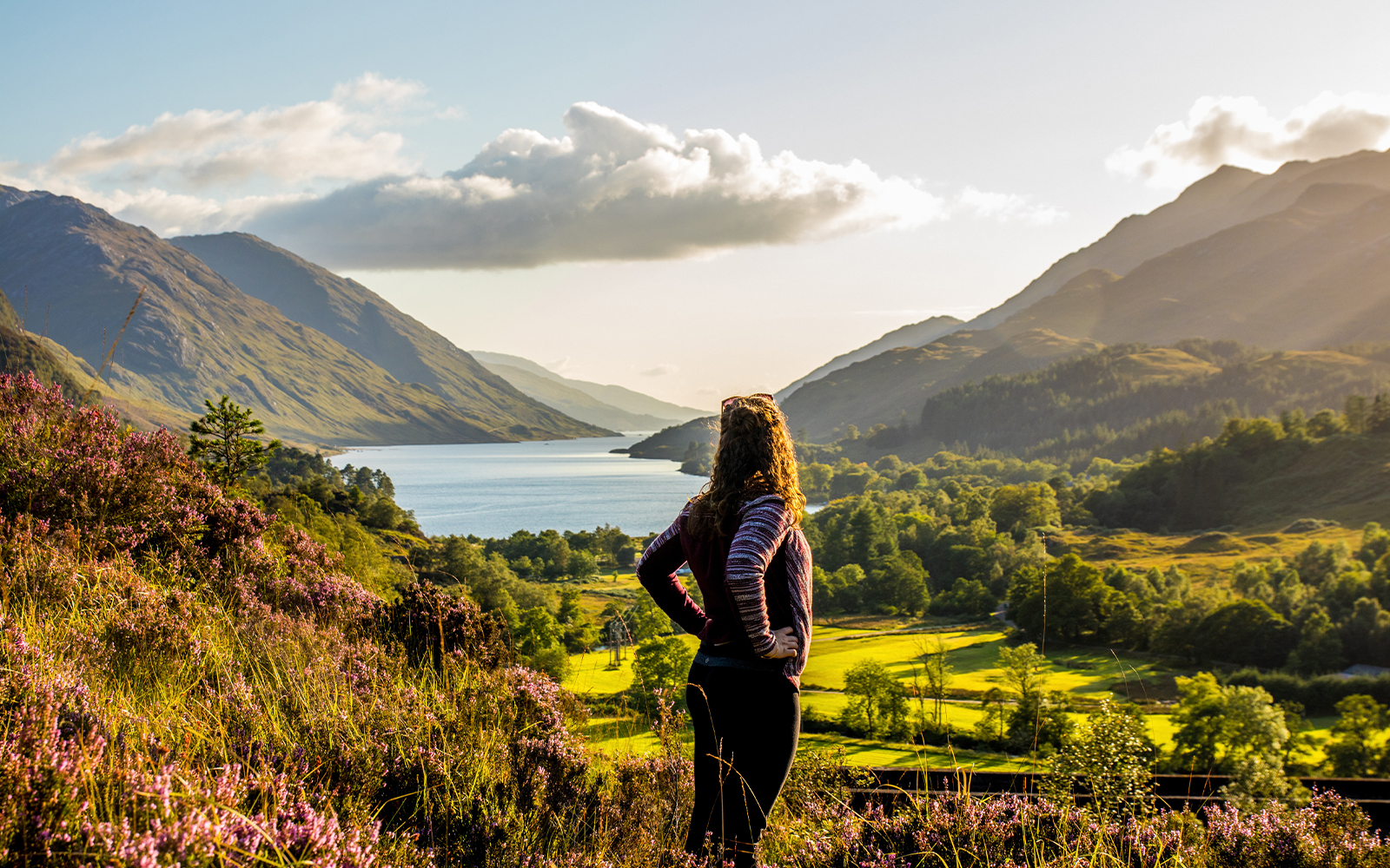 Girl overlooking a serene lake surrounded by lush greenery in Edinburgh.