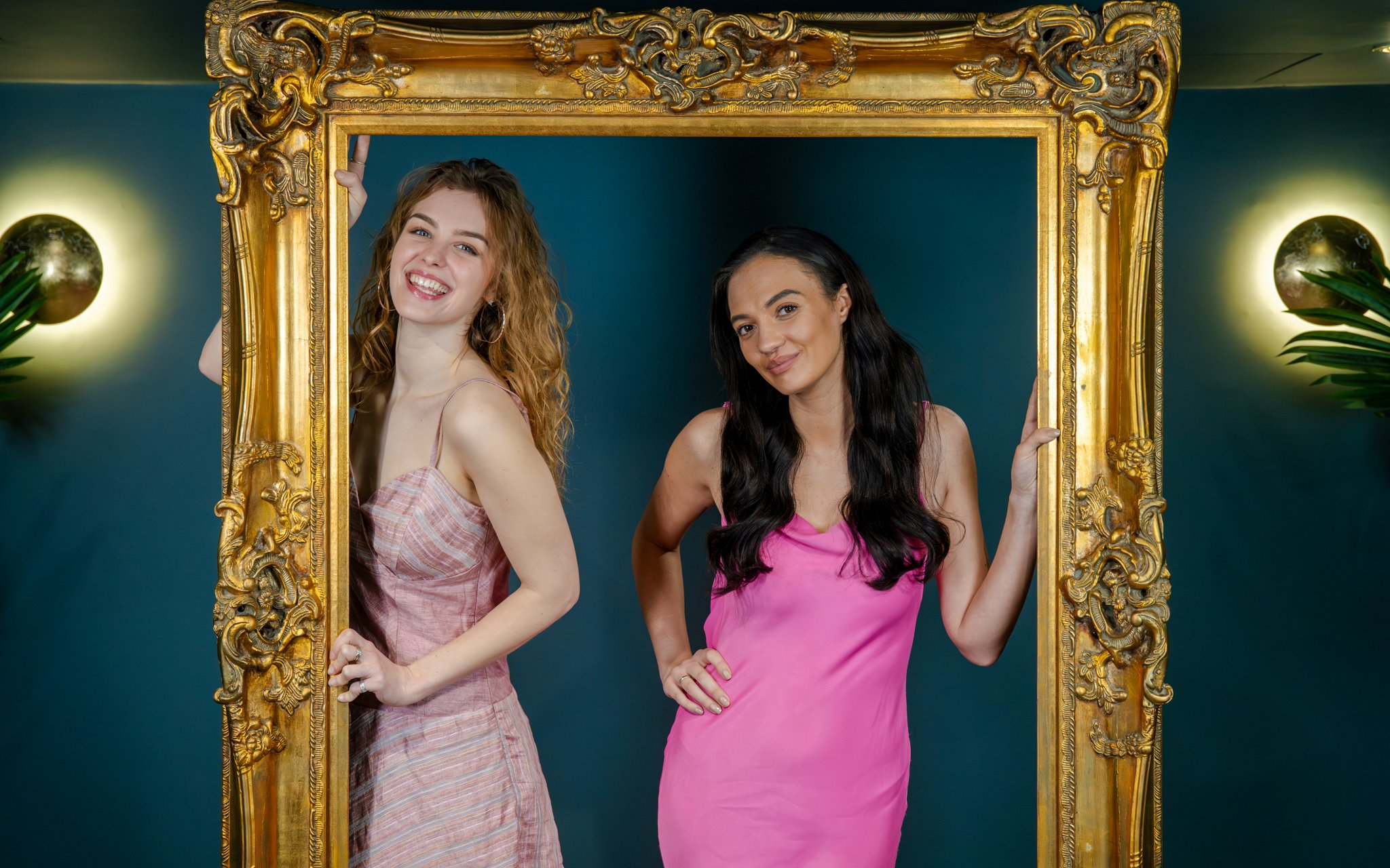 Guests posing with a golden frame at Madame Tussauds Champagne bar.