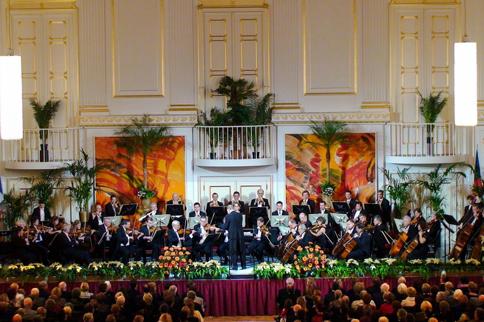 Vienna Hofburg Orchestra performing with musicians playing violins and flutes on stage.