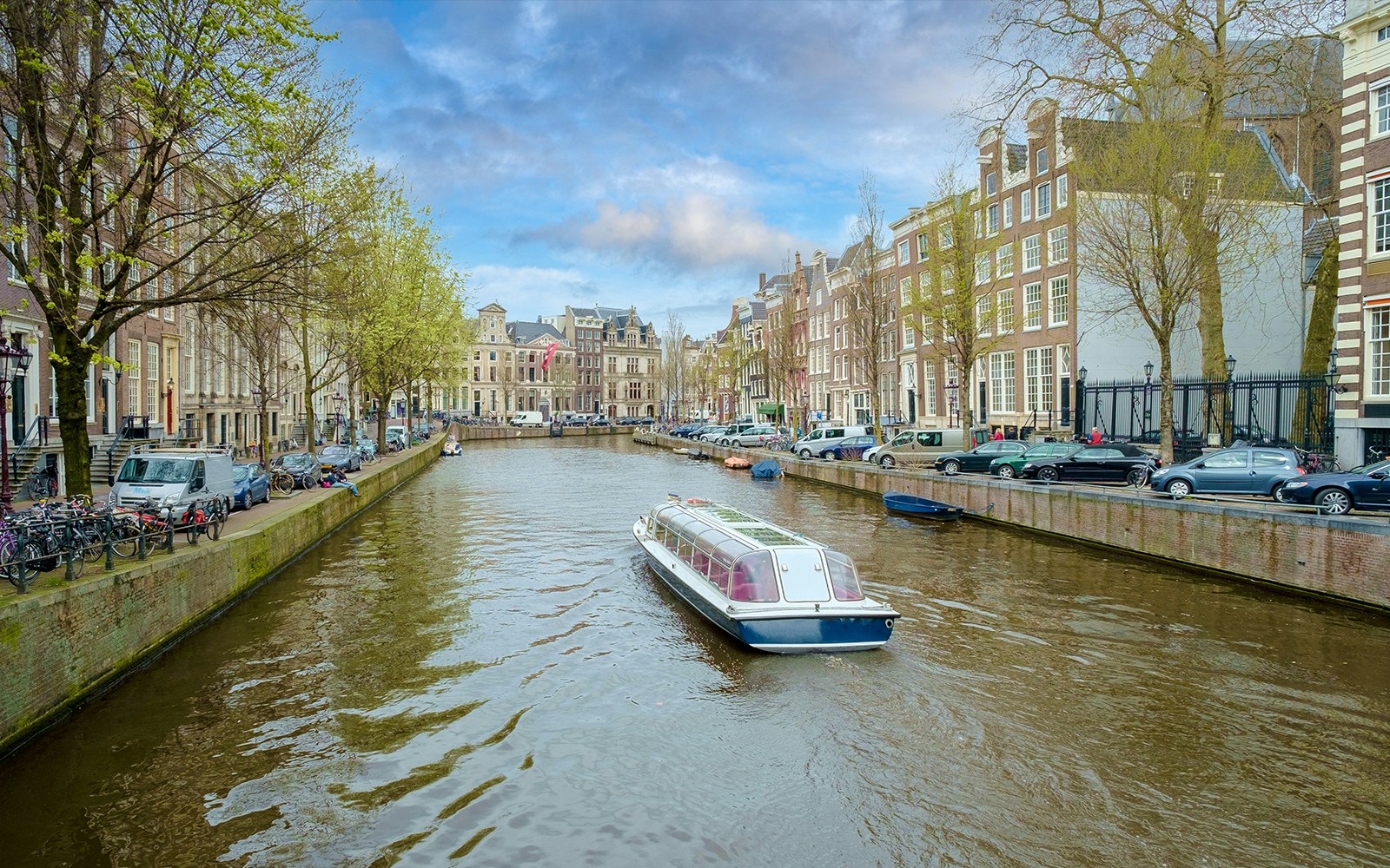 Canal boat on Herengracht in Amsterdam with historic buildings lining the waterway.