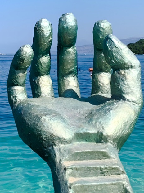 Sculpture of a hand emerging from the sea at Ksamil Beach, Albania.