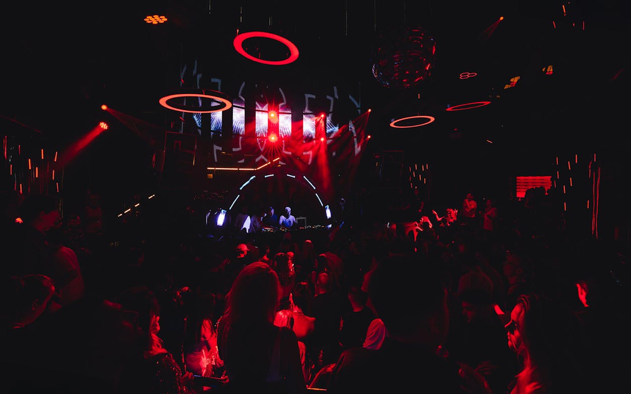 Nightclub scene with crowd and DJ under red lights at Eden on Mondays event.